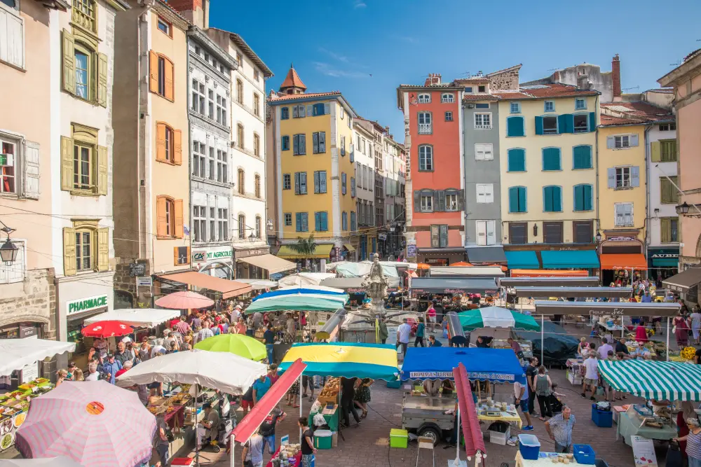 La très animée place du Plot, avec ses façades colorées et son marché, au Puy-en-Velay.