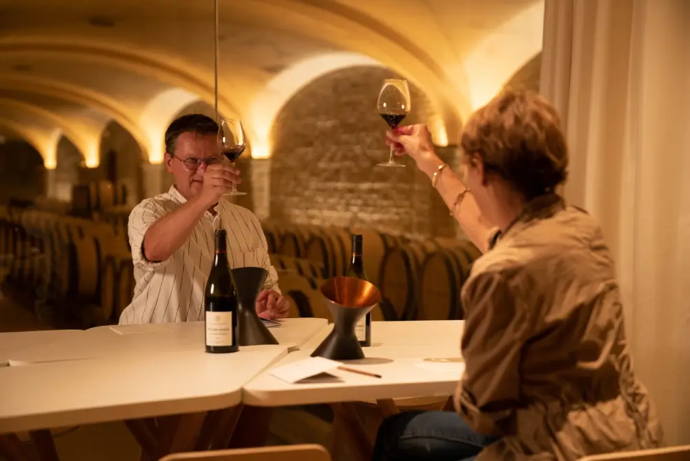 Un homme et une femme en train de déguster du vin dans une cave de Bourgogne.