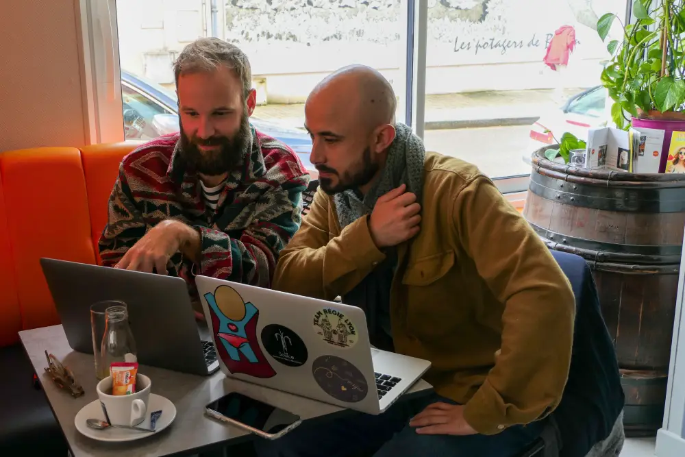 deux hommes en train de travailler avec leurs ordinateurs portables.