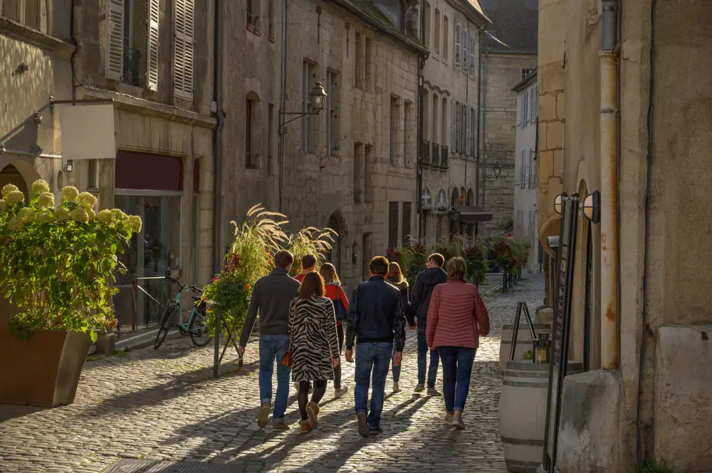 groupe de personnes de dos qui marchent dans la vielle ville de Dole.