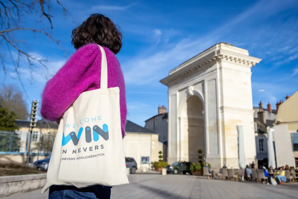 femme avec un sac "win - welcome in Nevers" dans la ville de Nevers.