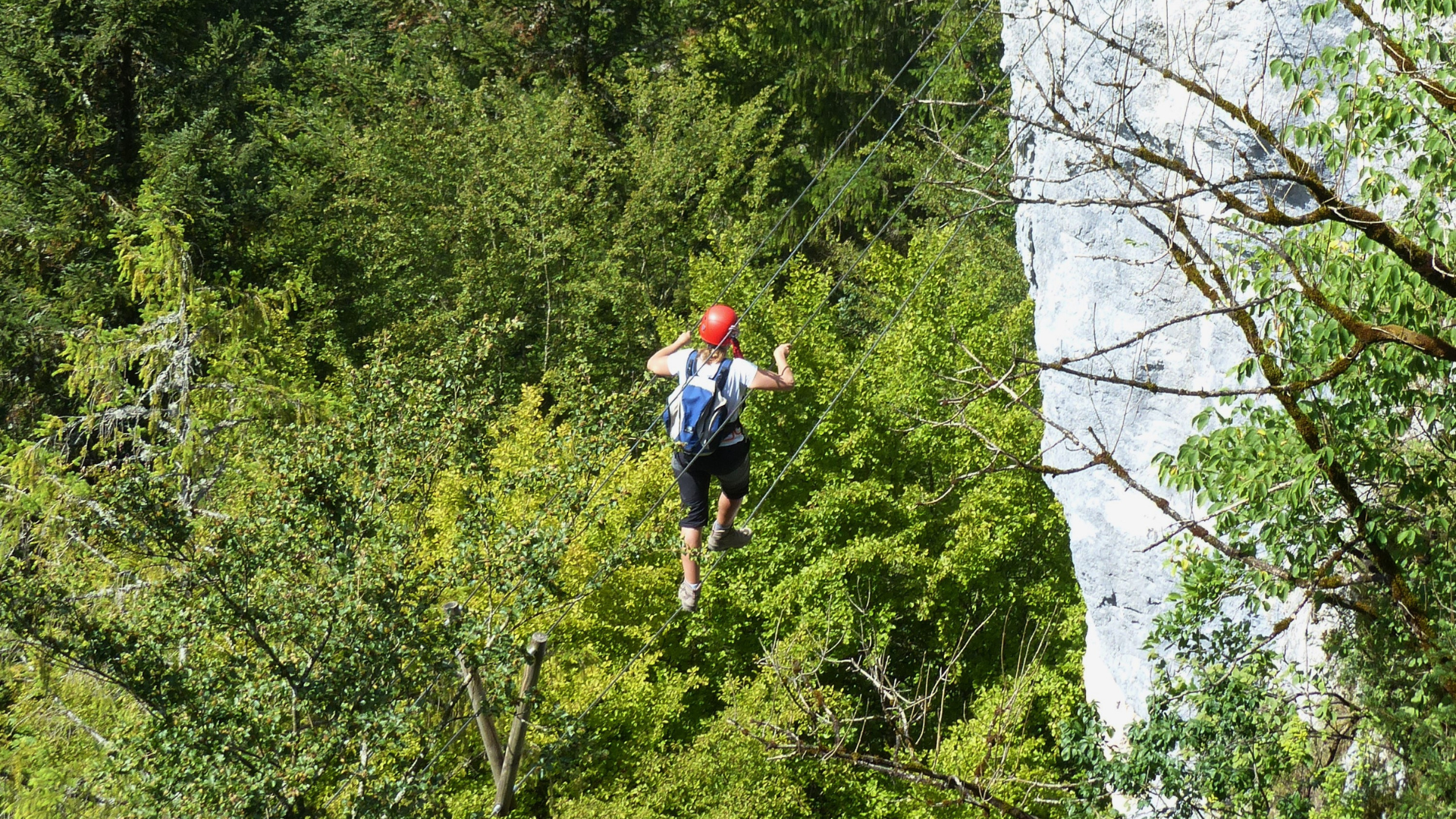 Vue sur les Échelles de la Mort de Charquemont, 1 personne sur des fils d'acier qui traverse entre deux roches. 