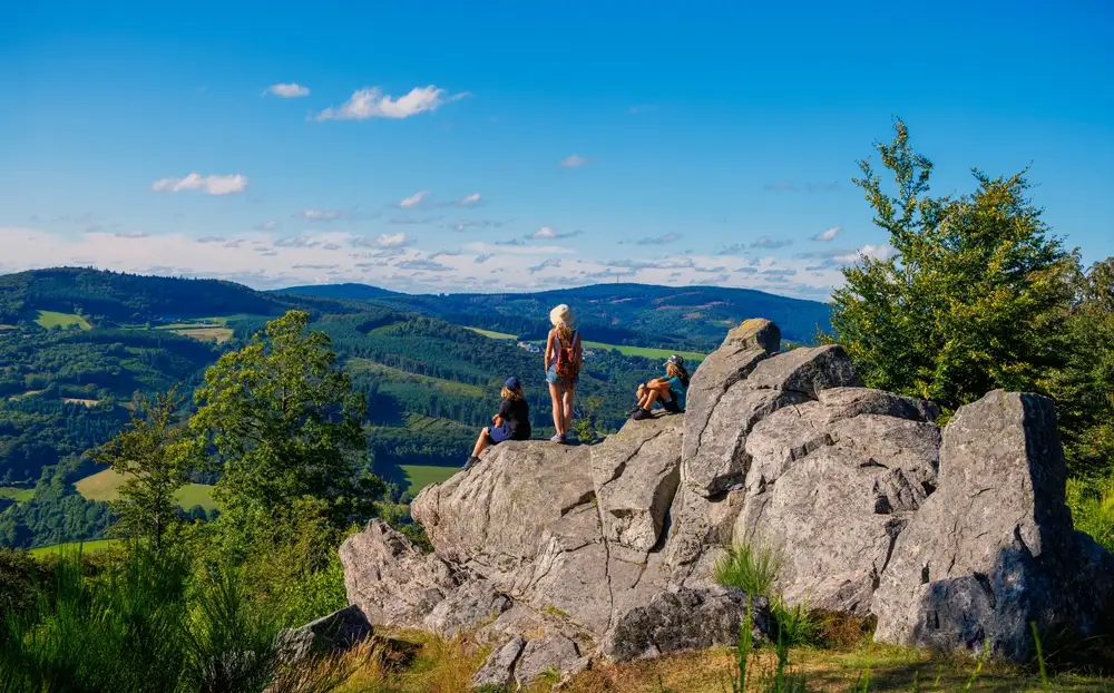 Vue du parc naturel régional du Morvan, trois personnes sur un rocher en hauteur face à une vue dégagée.