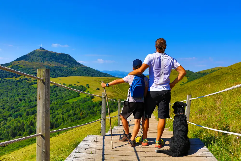 un père et son fils de dos face au Puy de Dôme en Auvergne par beau temps