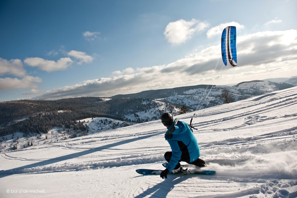 un skieur sur des pentes enneigées avec une aile de kyte.