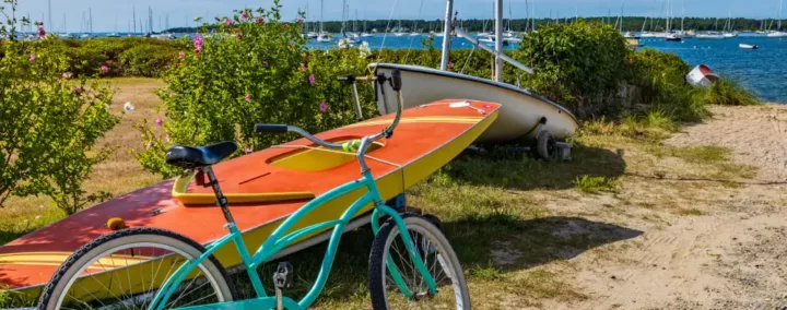 un vélo et un bateau à l'entrée d'un chemin qui mène à la plage.