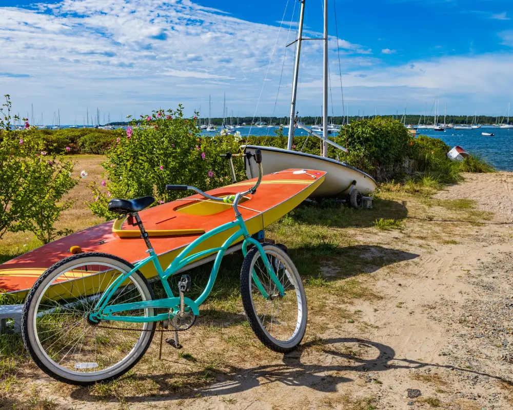 un vélo et un bateau à l'entrée d'un chemin qui mène à la plage.