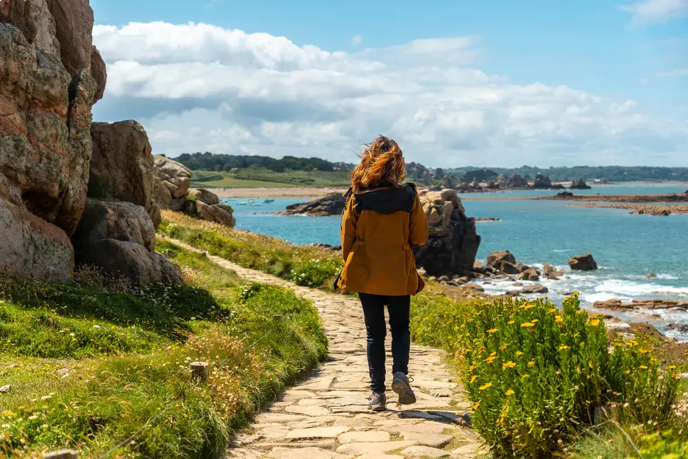 femme de dos qui marche sur un sentier de randonnée côtier à Plougrescant, dans les Côtes-d'Armor.