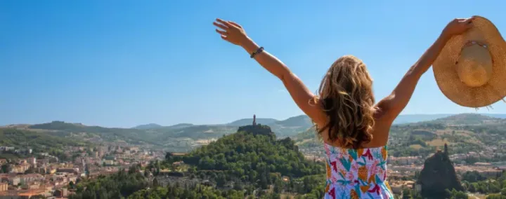 Femme de dos devant une vue de la ville du Puy en Velay, l'été